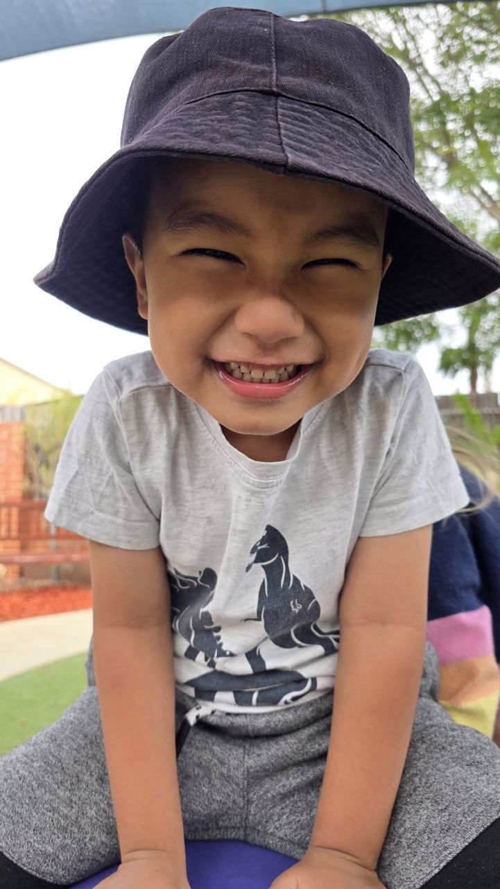 A child with a huge happy grin in a bucket hat